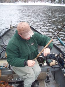 Man on a boat fishing with a center pin reel