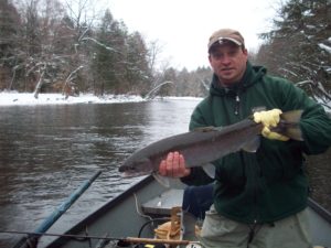 Angler on a boat poses with fish caught using center pin reels