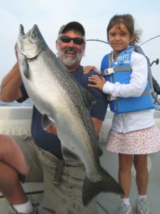 Man and young girl posing after being sucessful at salmon fishing on Lake Ontario.