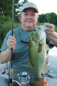 Woman holds up a smallmouth caught while bass fishing on the St. Lawrence River