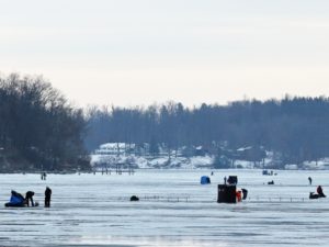 Ice fishing anglers and huts spread out over the ice on Sodus Bay. 