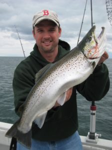 Man on a boat posing with a large brown trout on the eastern end of Lake Ontario.