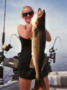 Woman poses with huge walleye caught while spring trolling, showing she knows how to troll fish in lakes.