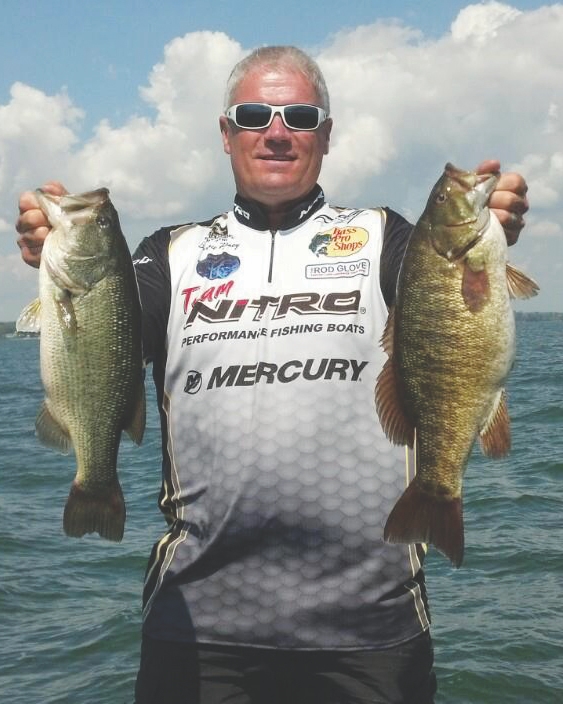 Man standing holding two big bass caught while swimbait fishing