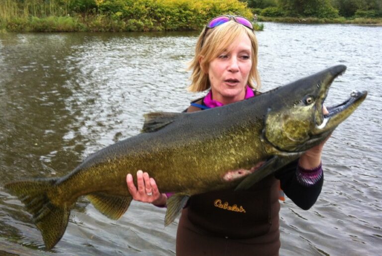 A fisherman holds up a large salmon.